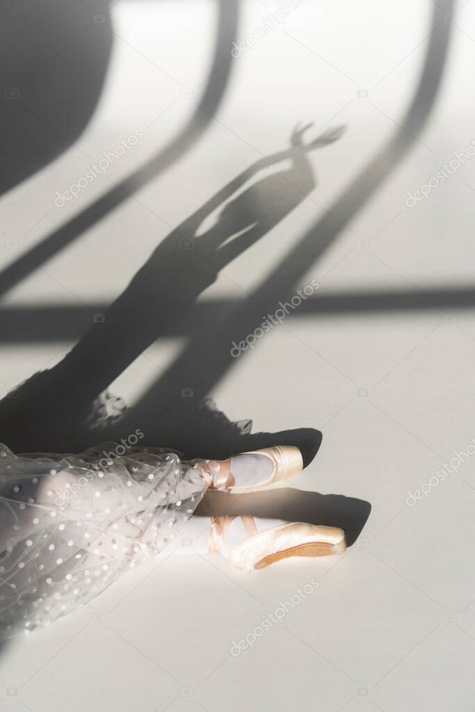 Cropped view of ballerina sitting on grey background 
