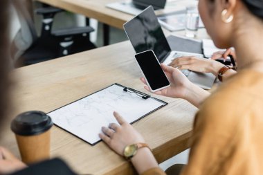 Tasarımcının akıllı telefonu çizim yakınında tutması ve iş yerinde iş arkadaşlarının