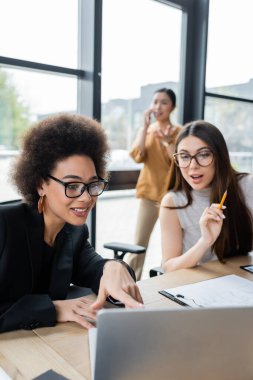 Gülümseyen Afro-Amerikan iş kadını bilgisayarını işaret ediyor.