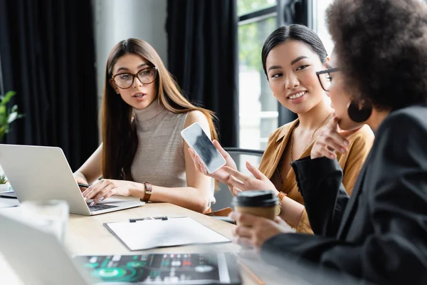 Smiling Asian Businesswoman Pointing Cellphone Blank Screen Interracial Colleagues — Stock Photo, Image