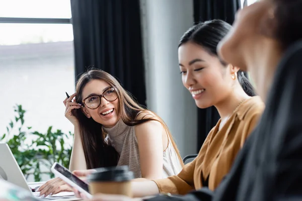 Gelukkig Aziatische Manager Zoek Naar Mobiele Telefoon Buurt Vrolijke Interraciale — Stockfoto