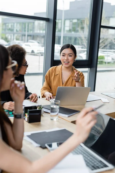 Positiva Asiática Empresária Apontando Com Mão Enquanto Conversa Com Colegas — Fotografia de Stock