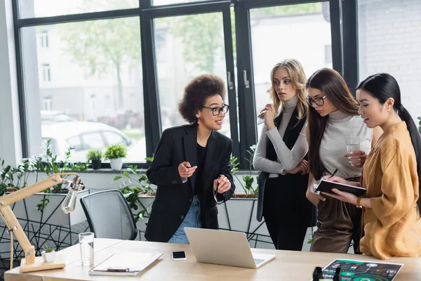 African American Woman Pointing Laptop While Talking Multiethnic Business Partners — Stock Photo, Image