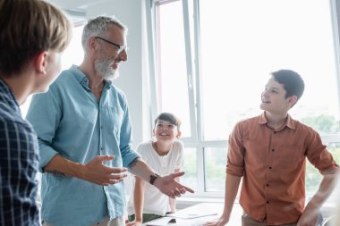 Sınıfta çok ırklı öğrencilerle konuşurken gülümseyen öğretmen hareketi