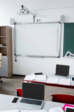 modern classroom with erase board on wall and digital devices on desks clipart