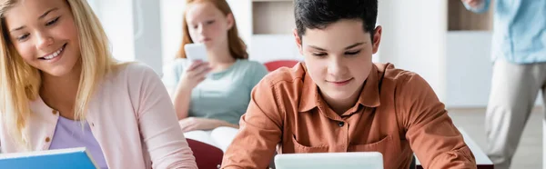 Schulkind Blickt Auf Verschwommenes Digitales Tablet Neben Lächelndem Klassenkameraden Banner — Stockfoto