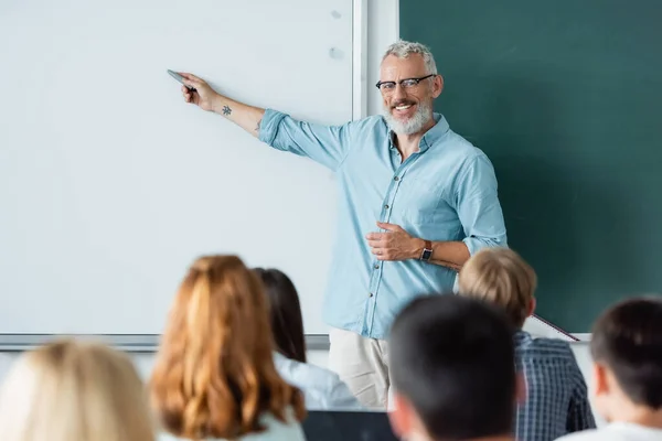 Profesor Sonriente Apuntando Tablero Borrado Cerca Las Pupilas Borrosas —  Fotos de Stock