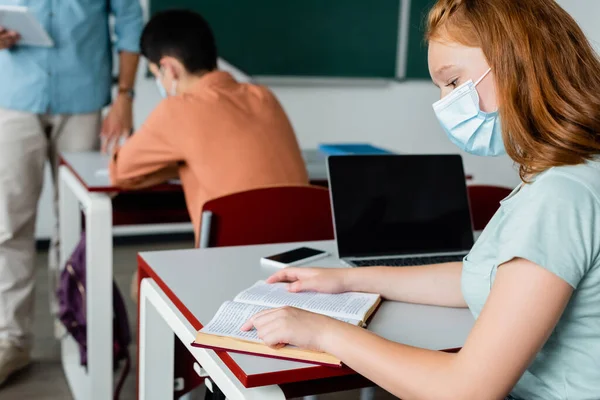 Colegiala Libro Lectura Máscara Médica Cerca Dispositivos Aula —  Fotos de Stock