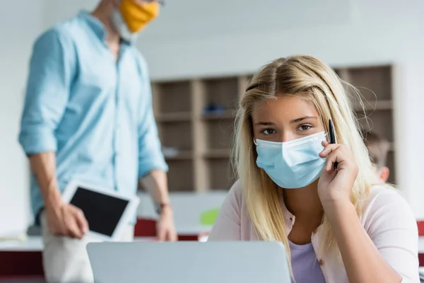 Schoolgirl Medical Mask Holding Pen Laptop Blurred Teacher — 스톡 사진