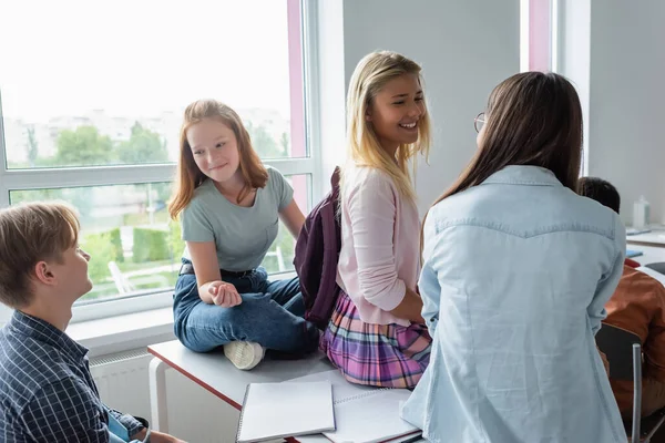 Χαμογελώντας Μαθήτριες Κάθεται Στο Τραπέζι Κοντά Συμμαθητή Κατά Διάρκεια Φρένων — Φωτογραφία Αρχείου