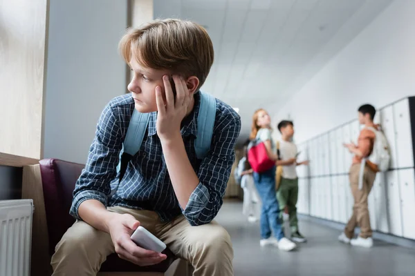 Niño Deprimido Con Teléfono Inteligente Sentado Solo Pasillo Escuela Cerca —  Fotos de Stock