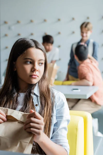 Frustrerad Flicka Sitter Med Papperspåse Matsal Nära Klasskamrater Suddig Bakgrund — Stockfoto