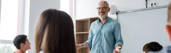 Happy Middle Aged Teacher Talking Teenage Pupils Blurred Foreground Banner — 스톡 사진