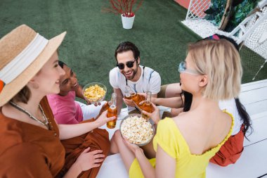 Patlamış mısır ve cips yakınındaki bira şişelerini tıkırdatan çok ırklı arkadaşların genel görünümü