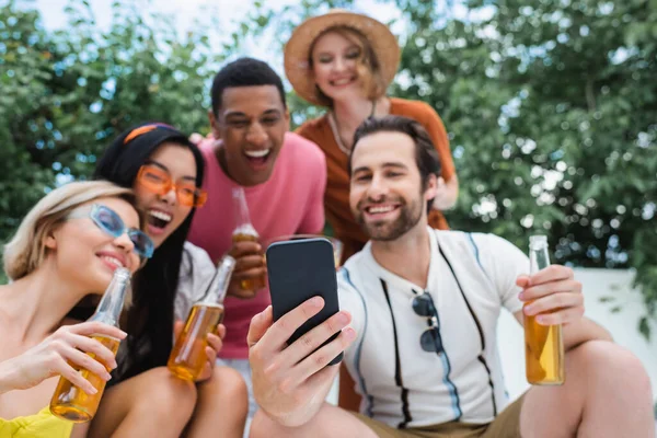 Homem Feliz Tomando Selfie Com Amigos Multiétnicos Borrados Durante Festa — Fotografia de Stock