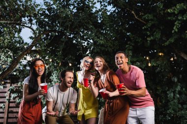 İçkili çok kültürlü arkadaşlar parti sırasında dışarıda karaoke söylüyorlar. 