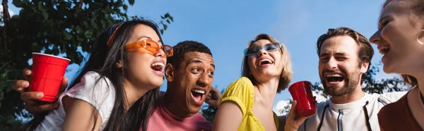 Low Angle View Interracial Friends Laughing While Holding Plastic Cups — Zdjęcie stockowe