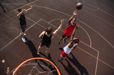 Overhead view of multiethnic sportsmen jumping while playing streetball clipart