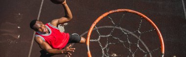 Top view of excited african american man playing basketball near hoop, banner  clipart