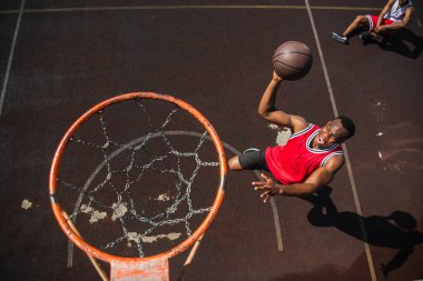Basketbol topuyla çember etrafında zıplayan heyecanlı Afrikalı Amerikalı adamın en iyi görüntüsü. 
