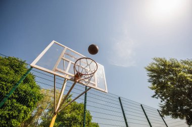 Low angle view of basketball ball near hoop on playground outdoors  clipart