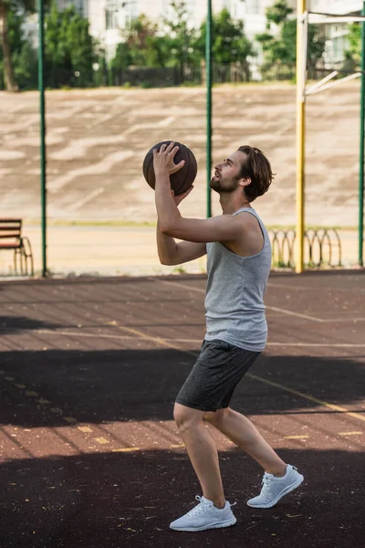 屋外の遊び場でバスケットボールボールを保持する若い男のサイドビュー — ストック写真
