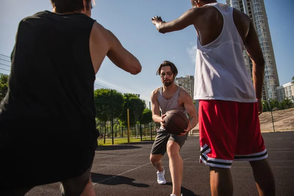 若いです男保持バスケットボールボール遊びながら多民族の友人と屋外 — ストック写真