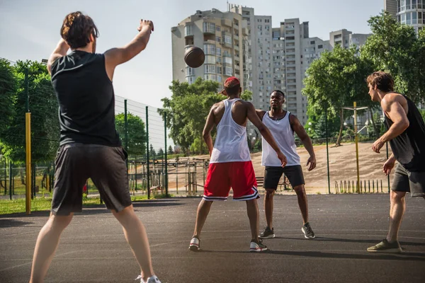 異人種間の男遊びバスケットボール近く友人とともに調達手上のぼやけた前景 — ストック写真