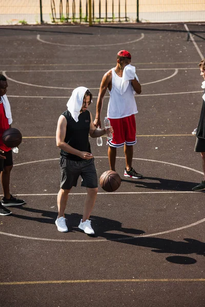 Молодой Человек Полотенцем Водой Стоит Рядом Баскетбольным Мячом Многонациональными Друзьями — стоковое фото