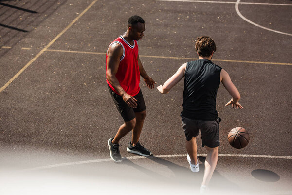 High angle view of interracial men playing basketball on court 