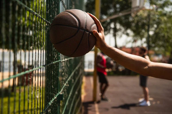 Widok Afrykański Amerykański Sportowiec Trzyma Piłkę Kosza Pobliżu Ogrodzenia Zewnątrz — Zdjęcie stockowe