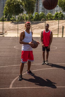 Afrika kökenli Amerikalı sporcular oyun bahçesinde basketbol topuna bakıyor. 