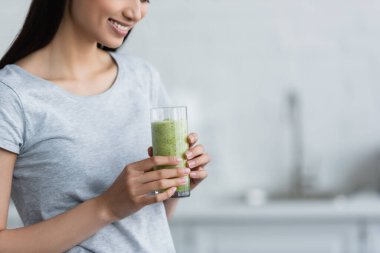 partial view of smiling woman holding glass of fresh homemade smoothie clipart