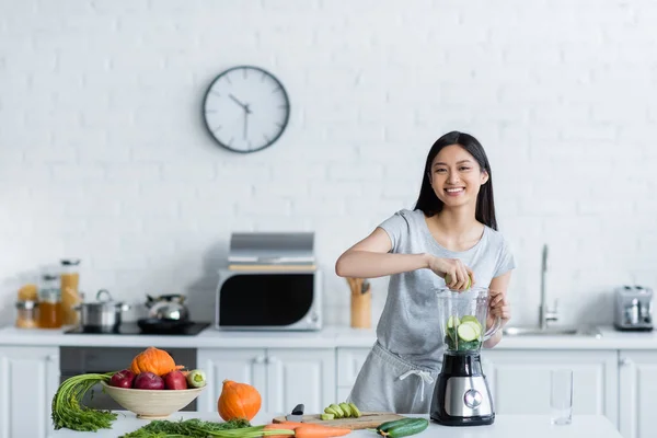 Азіатська Жінка Посміхається Камеру Додаючи Свіжі Овочі Електричний Шейкер — стокове фото