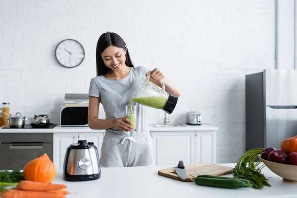 Sorrindo Asiático Mulher Derramando Caseiro Smoothie Perto Fresco Legumes Cozinha — Fotografia de Stock