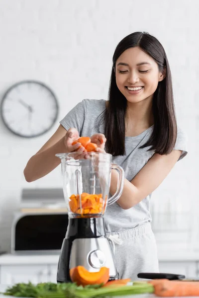 Cheerful Asian Woman Adding Sliced Carrot Electric Blender Cut Pumpkin — Stock Photo, Image