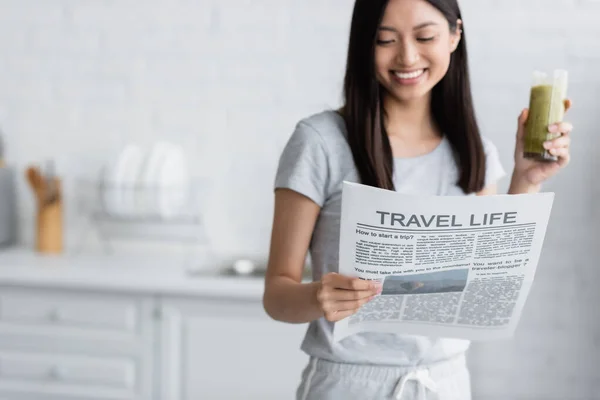 アジア系の女性がキッチンで旅行生活新聞を読んでいます — ストック写真