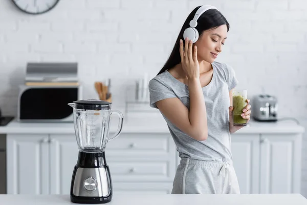 Pleased Asian Woman Glass Smoothie Listening Music Headphones Electric Shaker — Stock Photo, Image