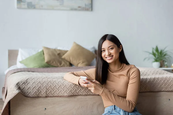 Freudige Asiatische Frau Lächelt Die Kamera Während Sie Ihr Smartphone — Stockfoto