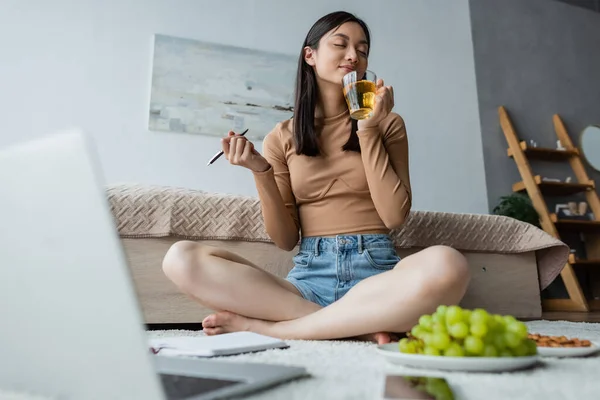 Nöjd Kvinna Njuter Smak Nära Suddig Laptop Och Druva Golvet — Stockfoto