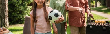 Çocuğun elinde futbol topu tutarken ailesinin ızgarada, pankartta yemek pişirdiği görüntüler. 
