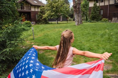 Çimlerde koşan Amerikan bayrağıyla genç bir çocuk. 