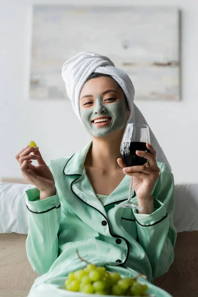 Cheerful Asian Woman Clay Mask Towel Head Holding Grape Red — Stock Photo, Image