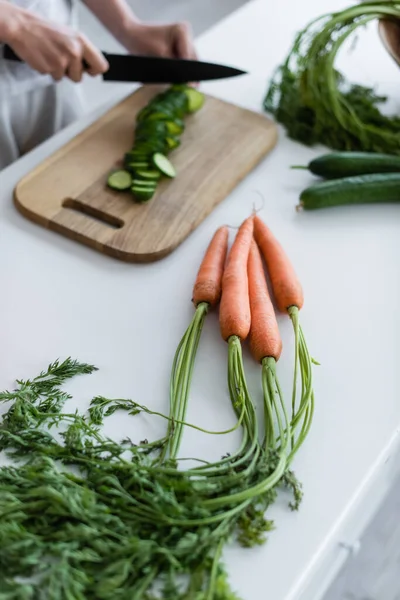 Vista Parcial Mujer Cortando Pepino Fresco Cerca Zanahorias Crudas Mesa —  Fotos de Stock