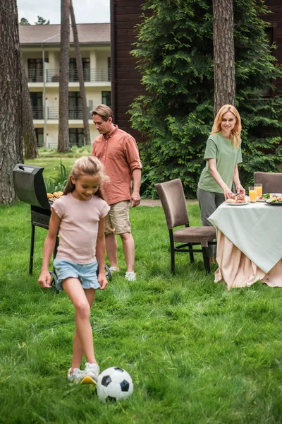 Sonriente Padre Cocina Comida Cerca Parrilla Niño Jugando Fútbol Césped —  Fotos de Stock