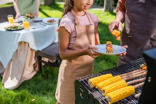 Vista Recortada Del Hombre Sosteniendo Verduras Parrilla Cerca Niño Sonriente — Foto de Stock