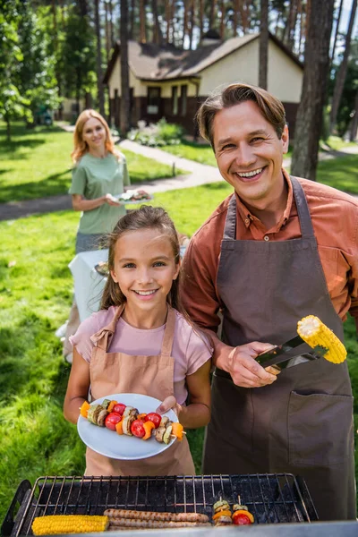 Father Smiling Kid Aprons Holding Grilled Vegetables Picnic — Stock Photo, Image