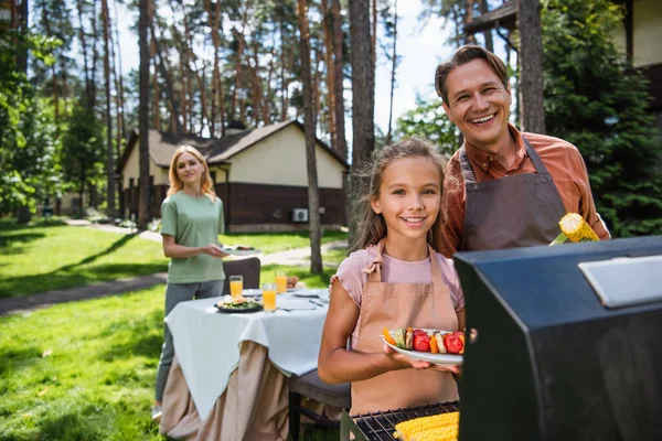 Padre Positivo Niño Sosteniendo Verduras Mientras Cocina Parrilla Cerca Madre — Foto de Stock