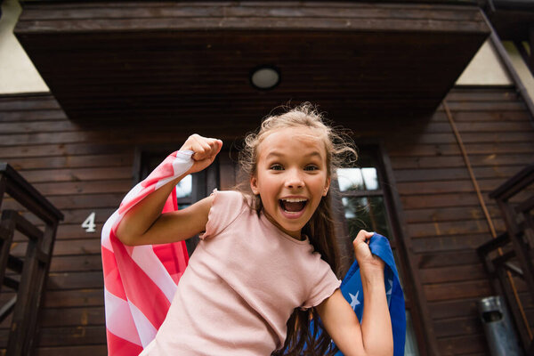 Excited girl holding american flag outdoors 