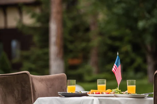 橙汁和美国国旗附近的味道鲜美的食物在户外桌上 — 图库照片